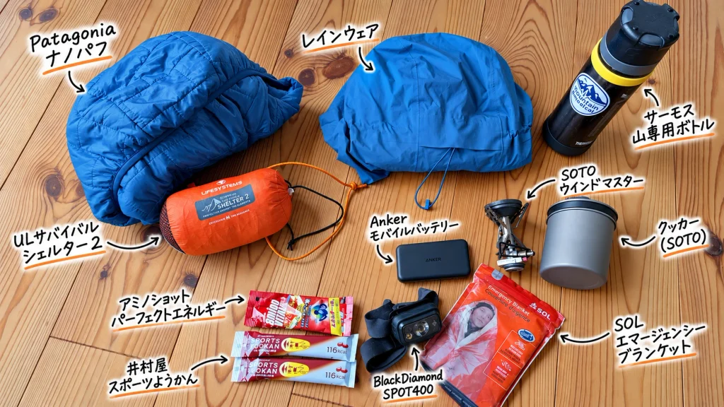 日帰り登山で携行するビバーク装備一式の写真。ULサバイバルシェルター2、Patagoniaナノパフ、レインウェア、サーモス山専用ボトル、SOTOウインドマスターとクッカー、Ankerモバイルバッテリー、BlackDiamond SPOT400、SOLエマージェンシーブランケット、井村屋スポーツようかん、アミノショットパーフェクトエネルギー。